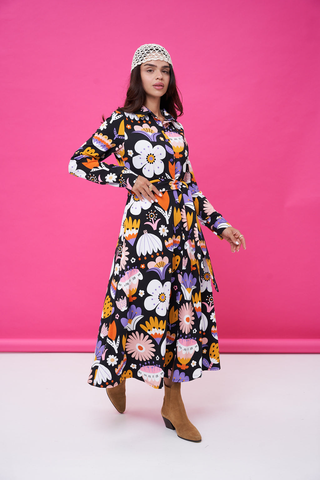 Woman wearing a colorful floral dress against a pink background