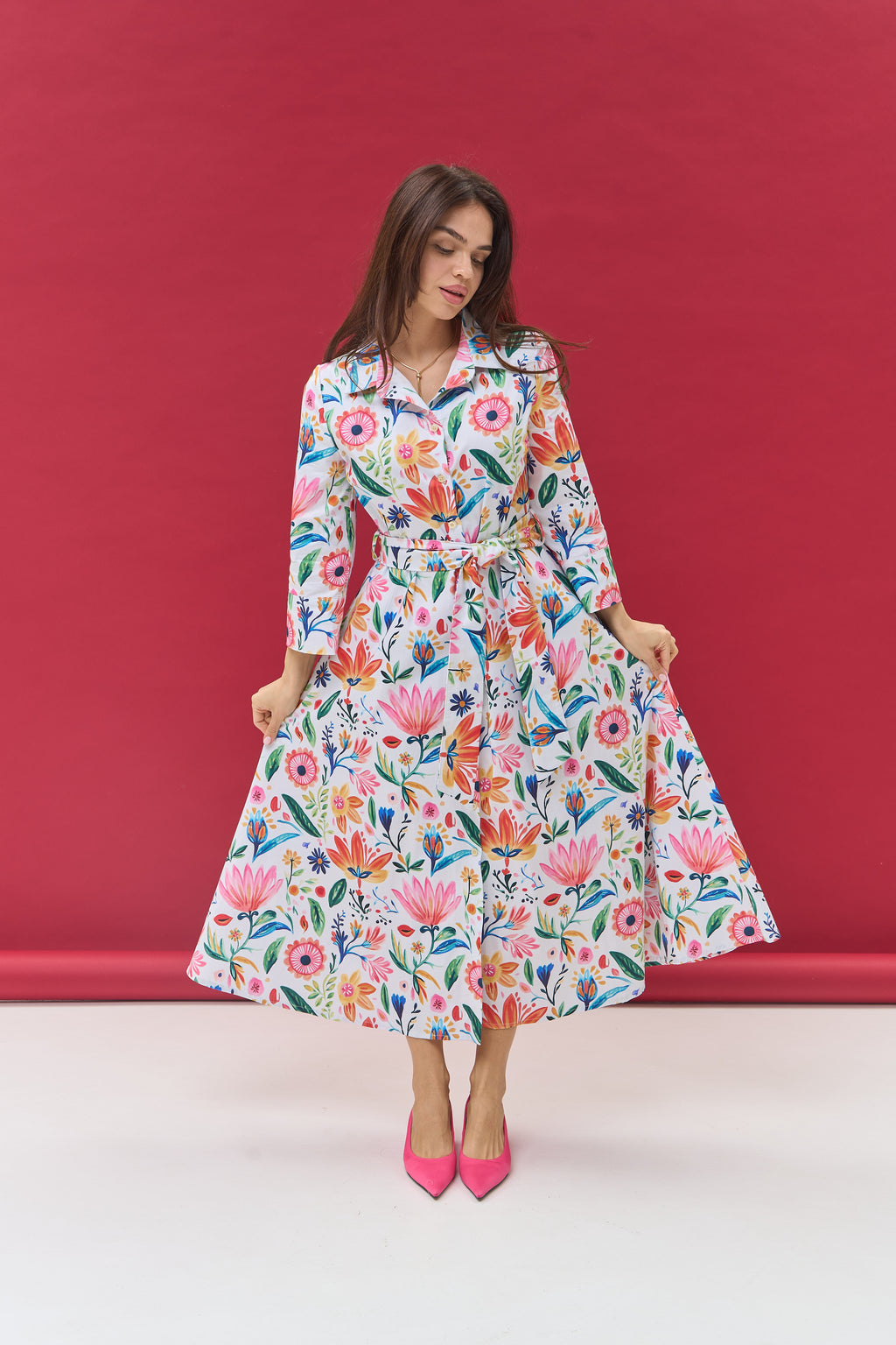 Woman wearing a colorful floral dress against a red background