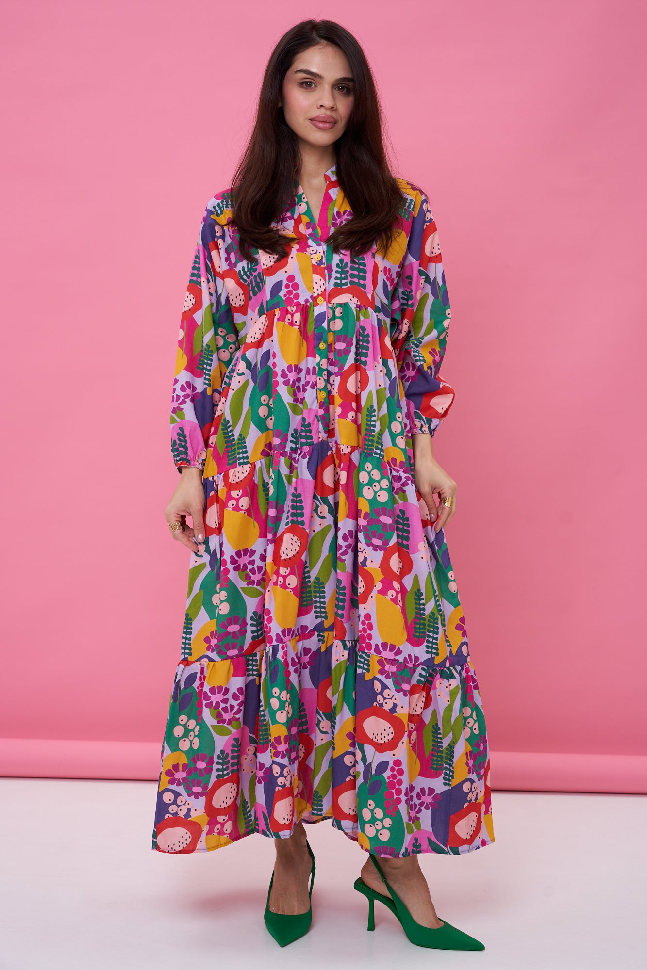 Woman wearing a colorful floral dress against a pink background