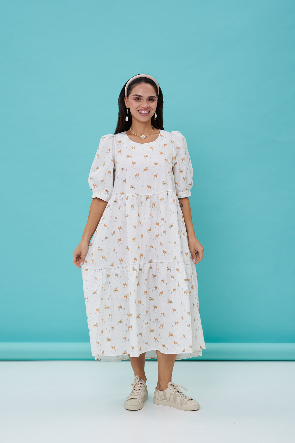 Woman wearing a white dress with a subtle pattern against a blue background